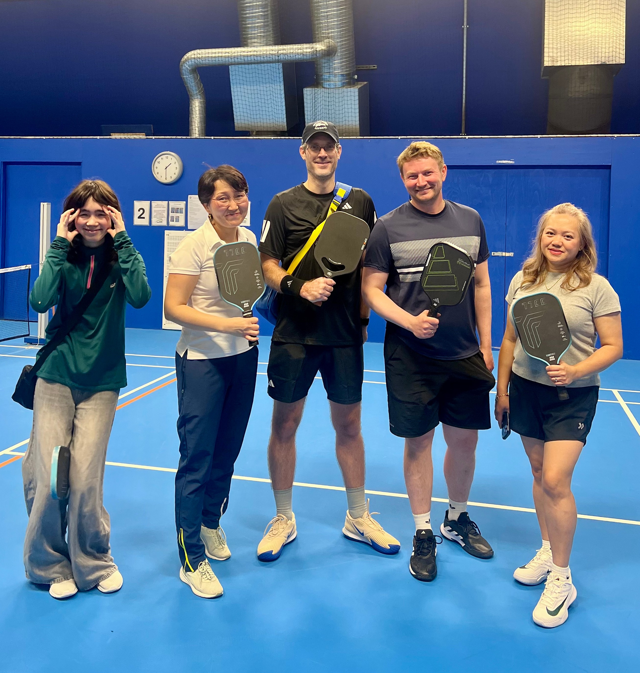 Five Nordball players with paddles on a blue indoor court